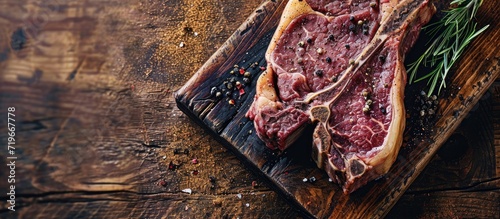Raw dry aged wagyu porterhouse beef steak with large fillet piece as closeup on a black burnt wooden board with copy space. Copy space image. Place for adding text photo