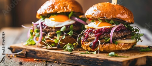 Two homemade beef burgers with mushrooms micro greens red onion fried eggs and beet sauce on wooden cutting board Side view close up. Copy space image. Place for adding text photo