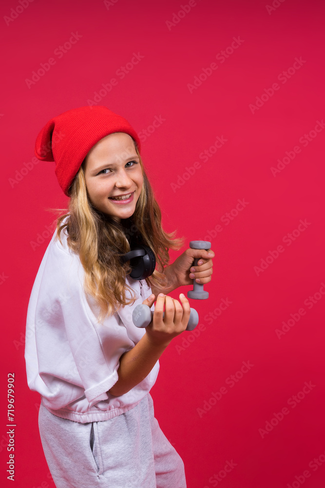 Kid girl doing fitness exercises with dumbbells on red background Kid girl doing fitness exercises with dumbbells on red background