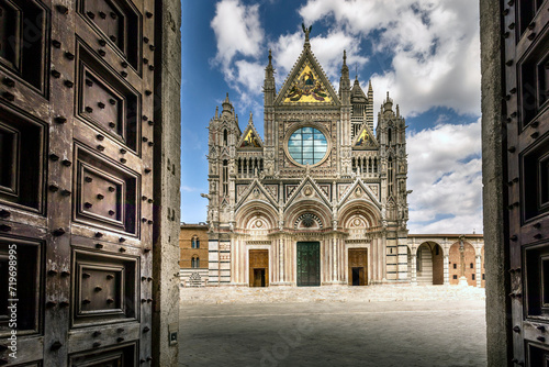 Siena, Italy - July 26, 2023: Siena Cathedral is a famous Italian Romanesque and Gothic cathedral with a striking facade is crowded with sculptures and boasts three large doors photo