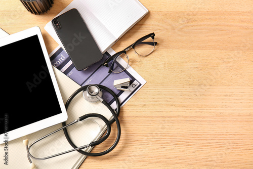 Tablet computer with mobile phone, notebooks and stethoscope on wooden medica...