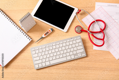 Computer keyboard with tablet and medical supplies on wooden desk, top view
