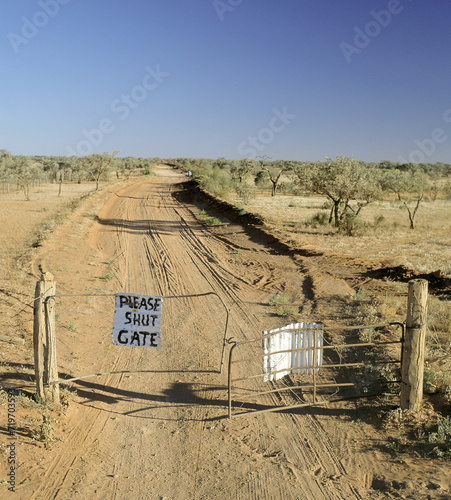 Dirt track in outback Queensland with please shut gate sign for passing travellers. photo