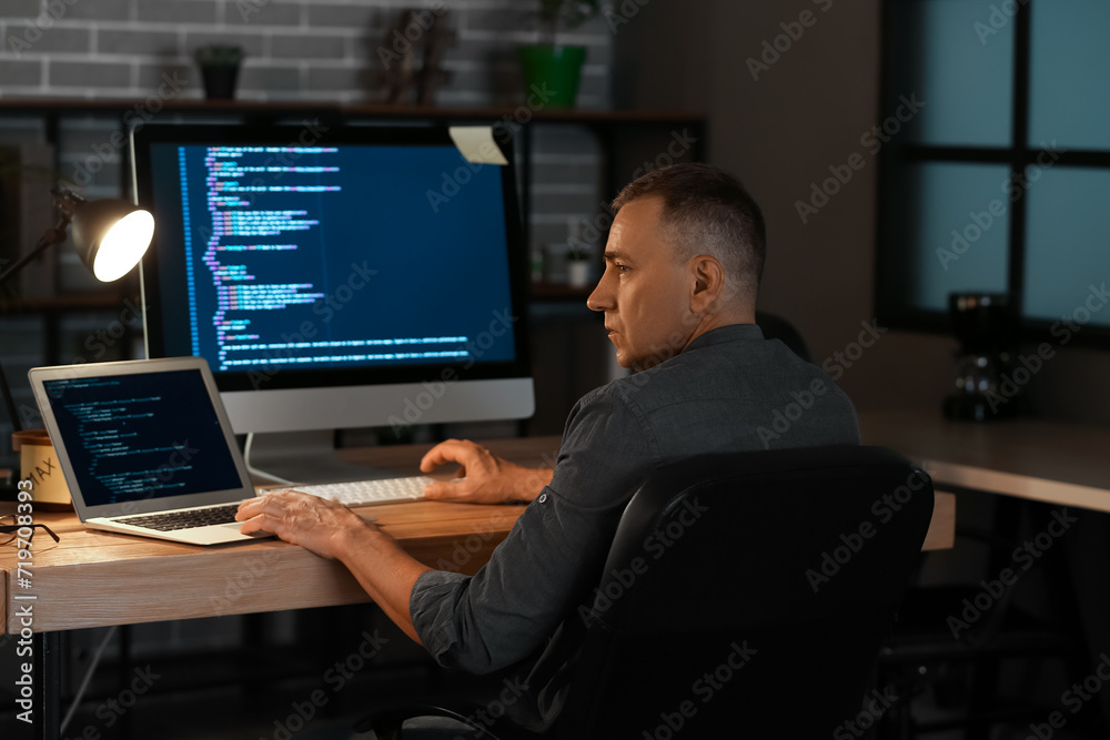 Mature male programmer working in office at night Mature male programmer working in office at night