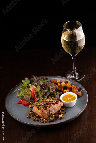 low carb dish of grilled salmon with salad and toast paired with white wine on wooden table