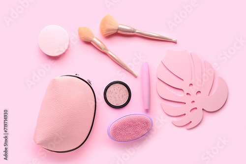 Composition with cosmetic bag with makeup brushes, mascara and highlighter on pink background
