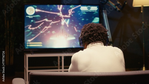 Gamer receiving game over screen on television set, getting his spaceship destroyed in huge explosion while fighting enemies. African american player losing science fiction spacecraft videogame