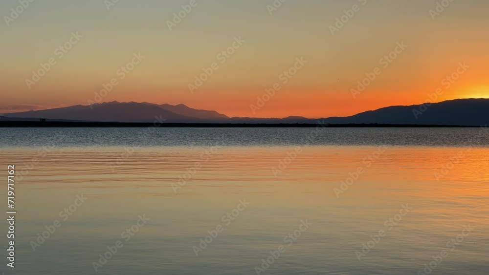 View of Issyk-Kul mountain lake at sunset, Kyrgyzstan. Waves splash on the beach with rocks. A calm, peaceful natural background. Sunset on the lake overlooking the Tien Shan Mountains. 4K View of Issyk-Kul mountain lake at sunset, Kyrgyzstan. Waves splash on the beach with rocks. A calm, peaceful natural background. Sunset on the lake overlooking the Tien Shan Mountains. 4K