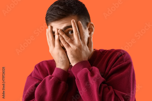 Afraid young man on orange ...