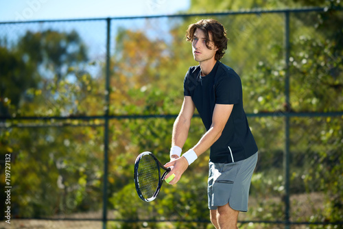 A young man hits a tennis ball on a tennis court © joescarnici