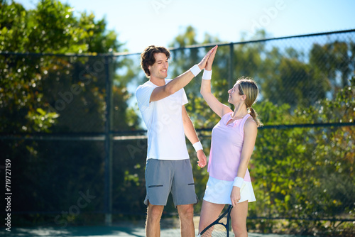 A male tennis coach gives a swing lesson to a female student © joescarnici