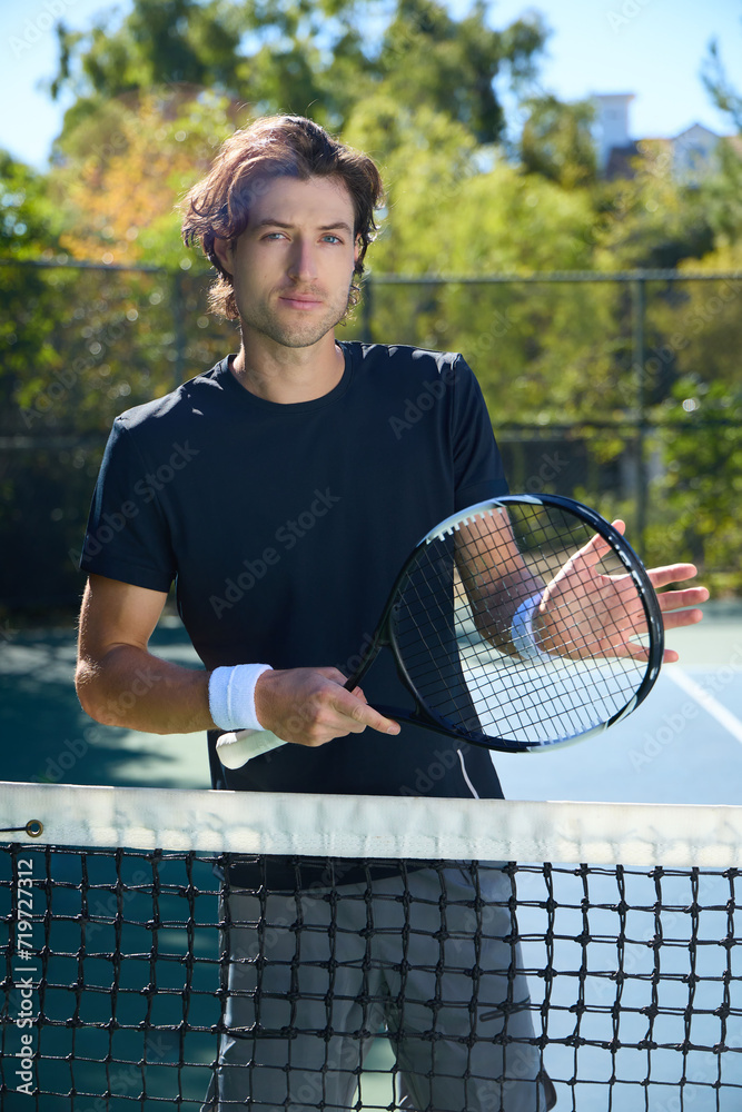 A male tennis player tests the tension of his tennis racket