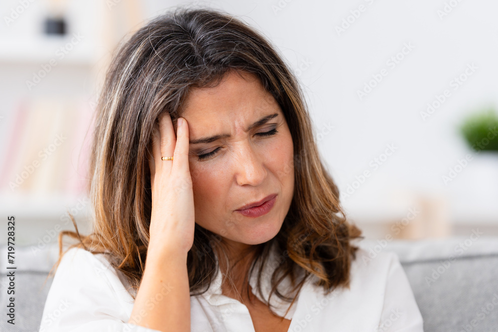 Close-up portrait of a mature woman gesturing headache at home alone Close-up portrait of a mature woman gesturing headache at home alone