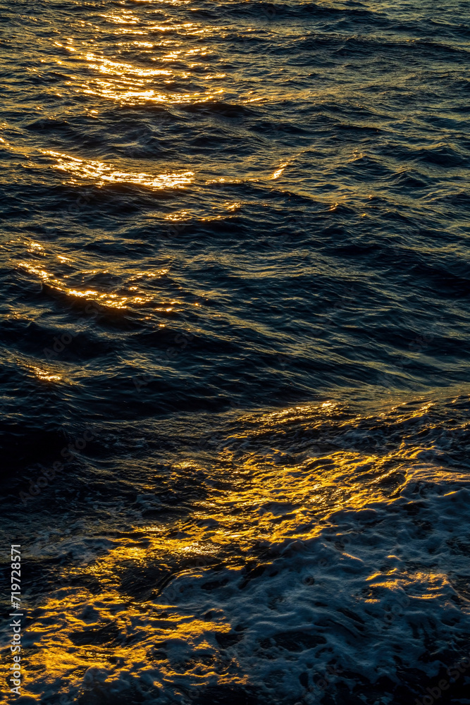 Rippled water surface at the sea during golden hour sunset close up