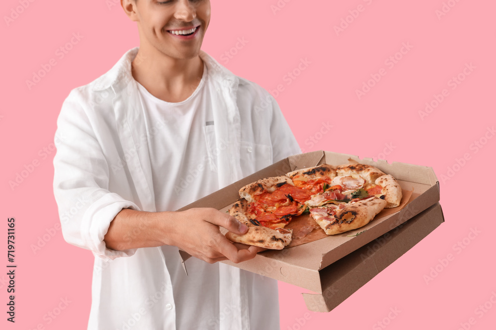 Young man with tasty pizza on pink background, closeup