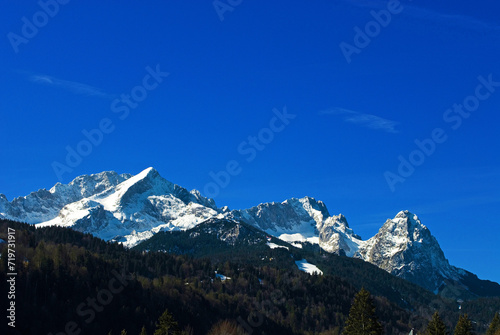 Mountain panorama of the snow-covered Wetterstein mountains in spring, with Alpspitze on the left, Zugspitze in the center and Waxenstein on the right, seen from Klais, Bavaria, Germany, Europe