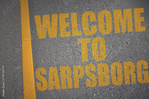 asphalt road with text welcome to Sarpsborg near yellow line. photo