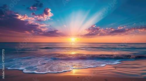 Colorful ocean beach sunrise with deep blue sky and sun rays.