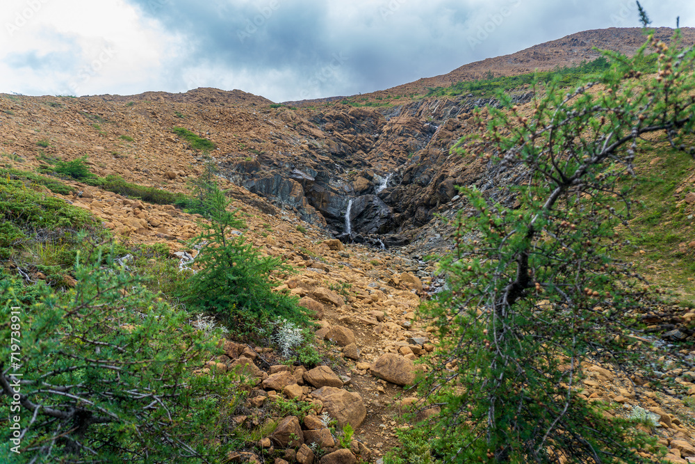 Fototapeta premium Tablelands in Gros Morne National Park, a Canadian national park and World Heritage Site in Newfoundland. An area where earth's mantle is exposed, peridotite rocks rich with iron rust, waterfall.