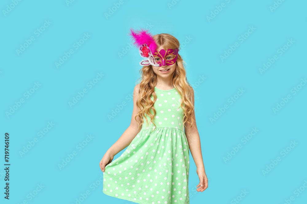 Funny little girl wearing carnival mask on blue background Funny little girl wearing carnival mask on blue background