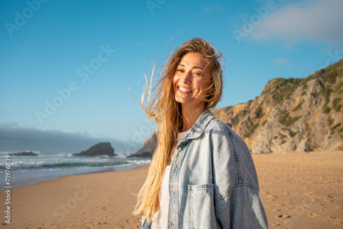 Fotografie Portrait of smiling woman with long blond hair on sandy beach