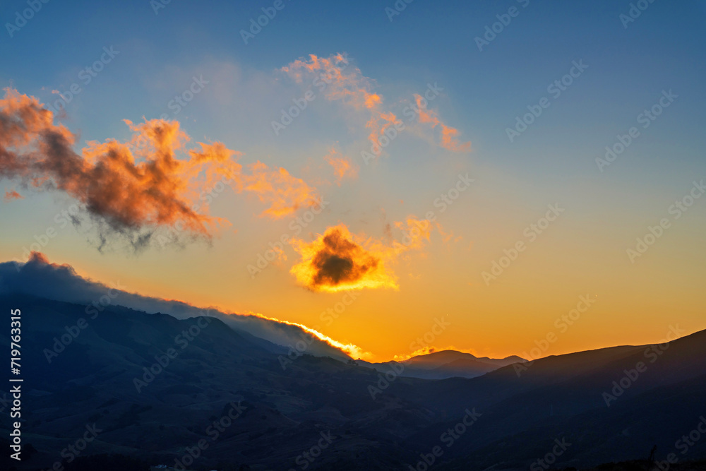 Sunrise in the mountains with glowing clouds