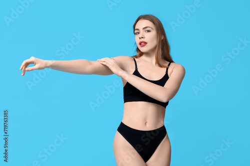Pretty young woman in black cotton underwear on blue background