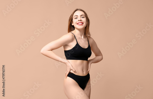 Sexy young woman in black cotton underwear on beige background