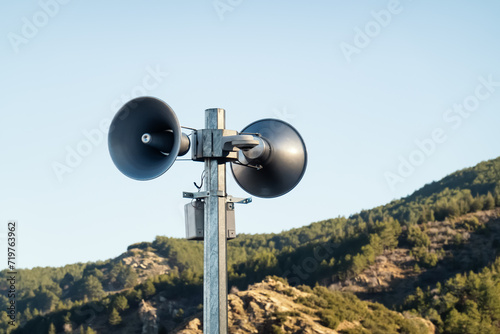 Loudspeakers on pole. Two public address system speakers on blue sky and mountains background