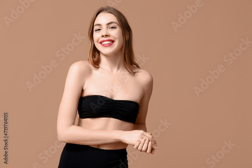 Attractive young woman in black underwear on beige background