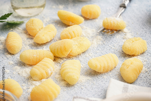 Fork with tasty gnocchi and flour on light background, closeup