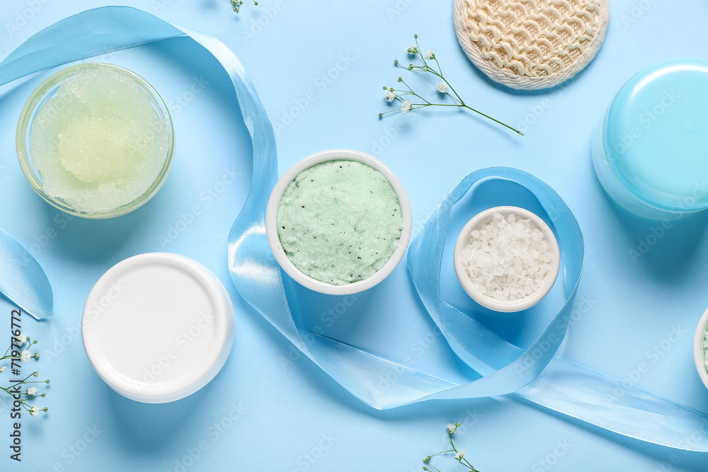 Scrubs with sea salt, cream and decor on blue background. Body massage concept Scrubs with sea salt, cream and decor on blue background. Body massage concept