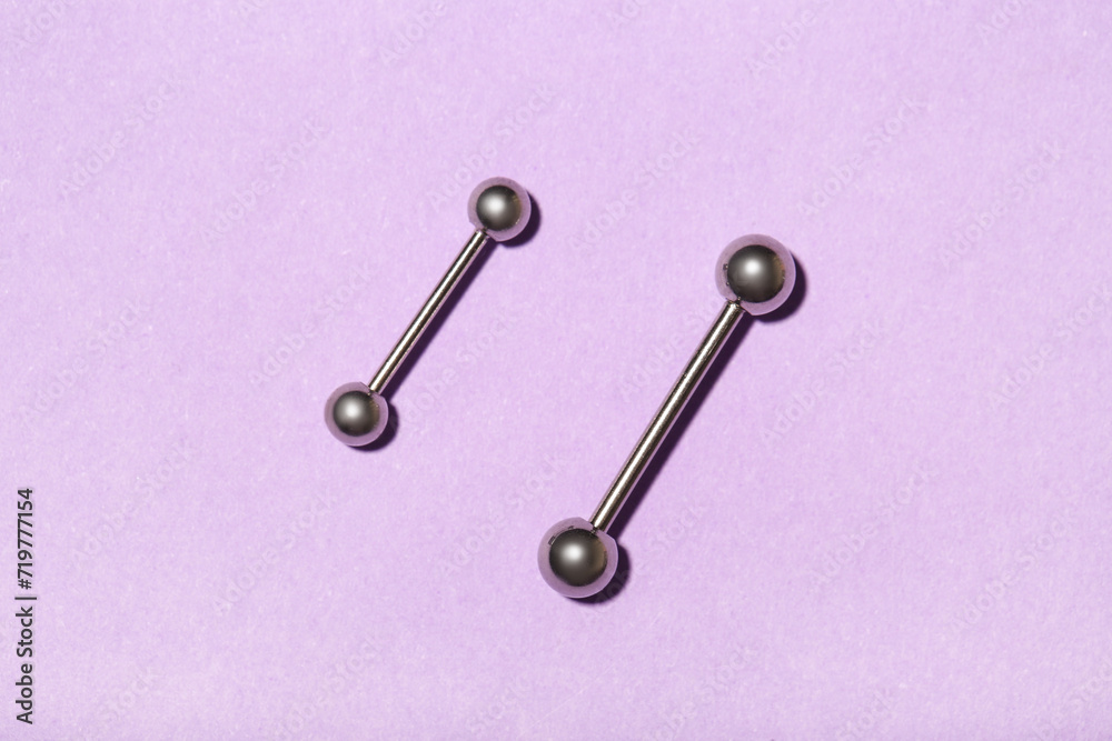 Barbells for piercing on lilac background Barbells for piercing on lilac background