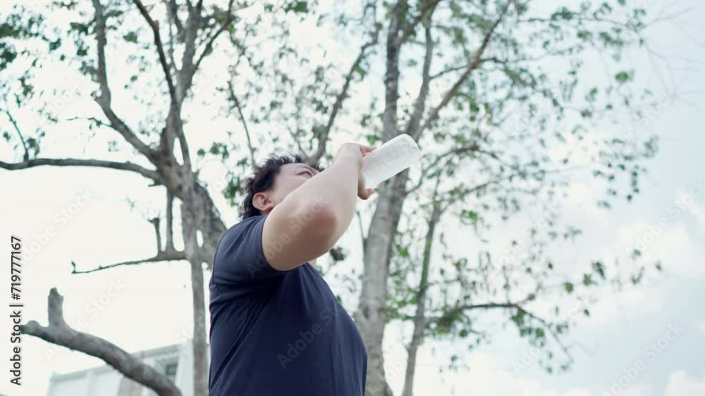 Man drinking water from a plastic bottle water after workout in forest Man drinking water from a plastic bottle water after workout in forest