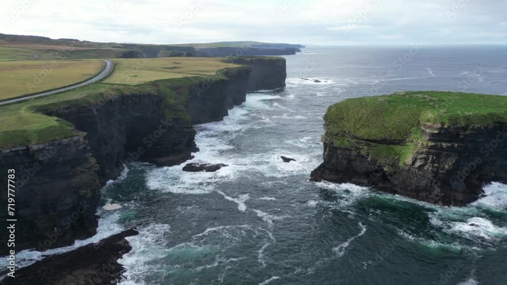 Kilkee Cliffs in Ireland with waves crashing against the rugged coastline, serene natural beauty, aerial view Kilkee Cliffs in Ireland with waves crashing against the rugged coastline, serene natural beauty, aerial view