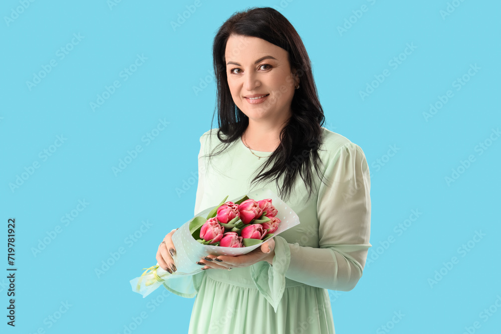 Beautiful happy mature woman with bouquet of tulips on blue background. International Women's Day Beautiful happy mature woman with bouquet of tulips on blue background. International Women's Day