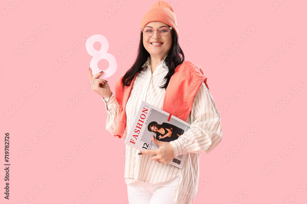 Beautiful happy mature woman with paper number 8 and magazine on pink background. International Women's Day Beautiful happy mature woman with paper number 8 and magazine on pink background. International Women's Day