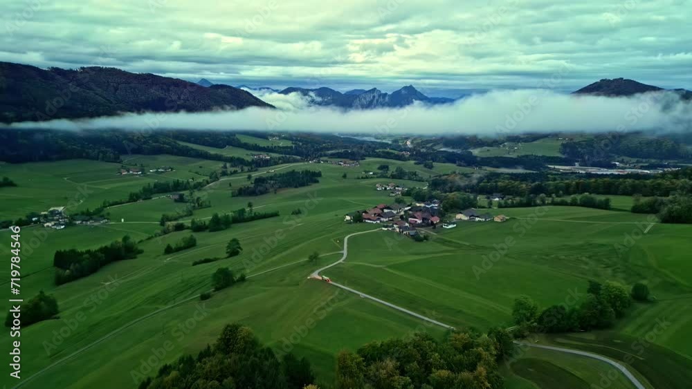 Bus driving to alpine mountain valley village, cloud hovering over it. Bus driving to alpine mountain valley village, cloud hovering over it.