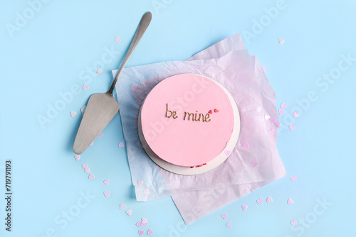 Pink bento cake with spatula and confetti on blue background. Valentine's Day celebration