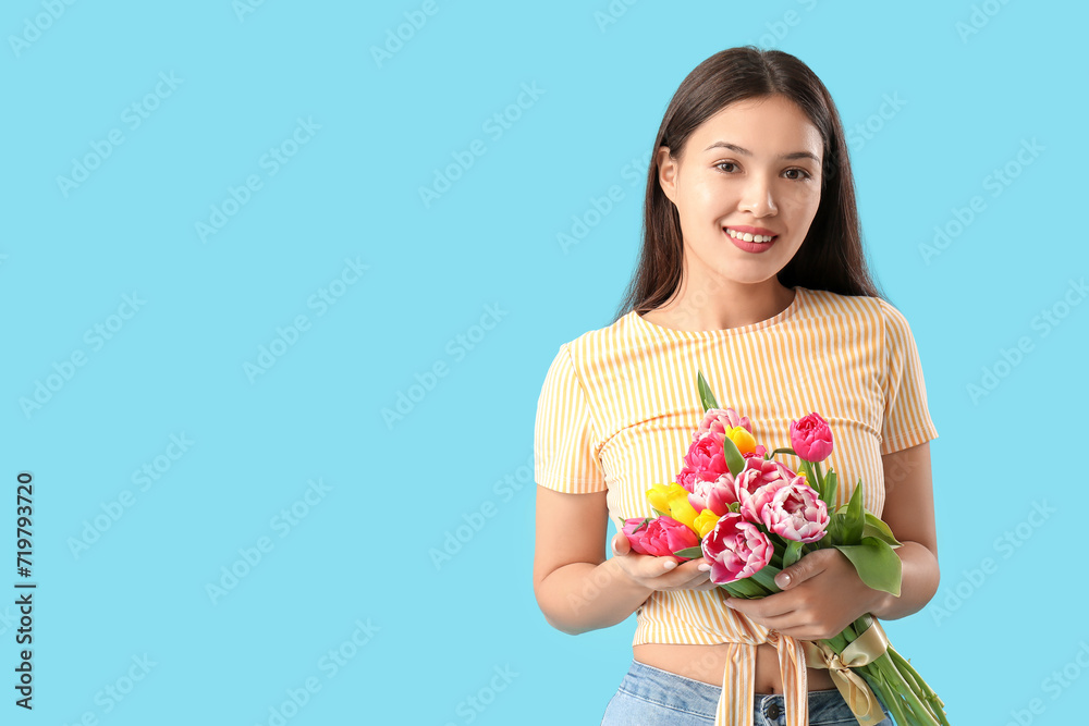 Happy young Asian woman with bouquet of beautiful tulips on blue background. International Women's Day Happy young Asian woman with bouquet of beautiful tulips on blue background. International Women's Day