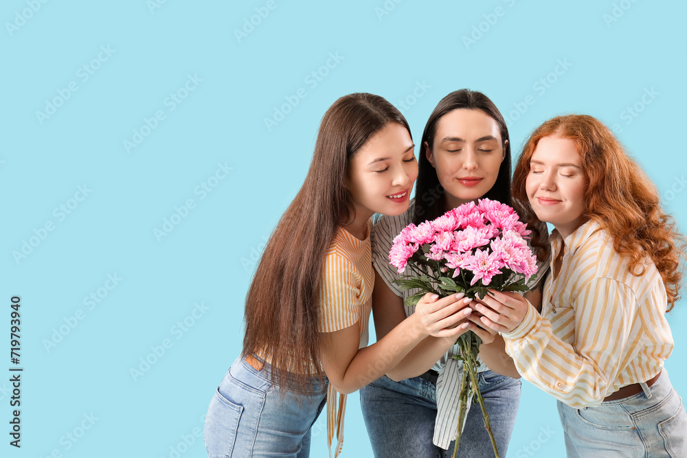 Beautiful young women with bouquet of pink chrysanthemum flowers on blue background. International Women's Day Beautiful young women with bouquet of pink chrysanthemum flowers on blue background. International Women's Day