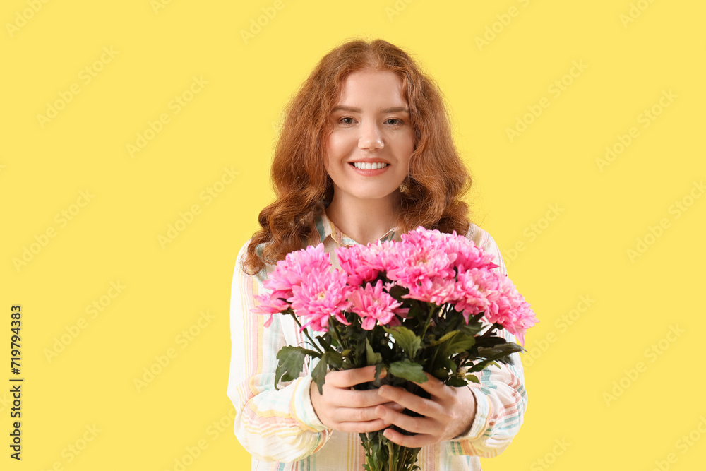 Happy young woman with bouquet of pink chrysanthemum flowers on yellow background. International Women's Day