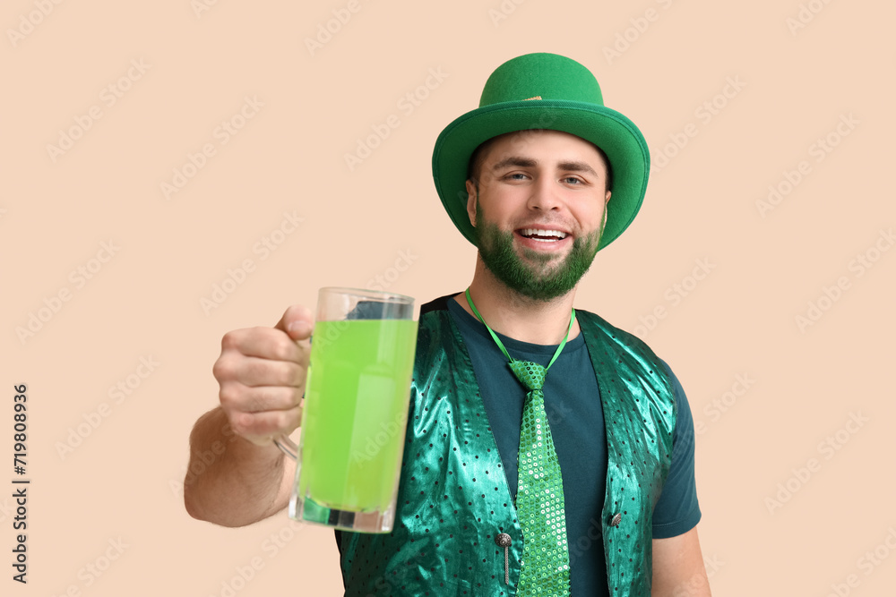 Young man in leprechaun hat with green beard holding glass of beer on beige background. St. Patrick's Day celebration Young man in leprechaun hat with green beard holding glass of beer on beige background. St. Patrick's Day celebration
