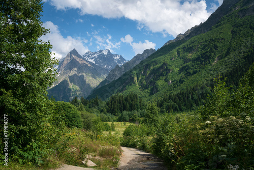 View of the Dombay-Ulgen gorge in the mountains of the North Caucasus and the trail to the Chuchkhur waterfall near the village of Dombay on a sunny summer day, Karachay-Cherkessia, Russia photo