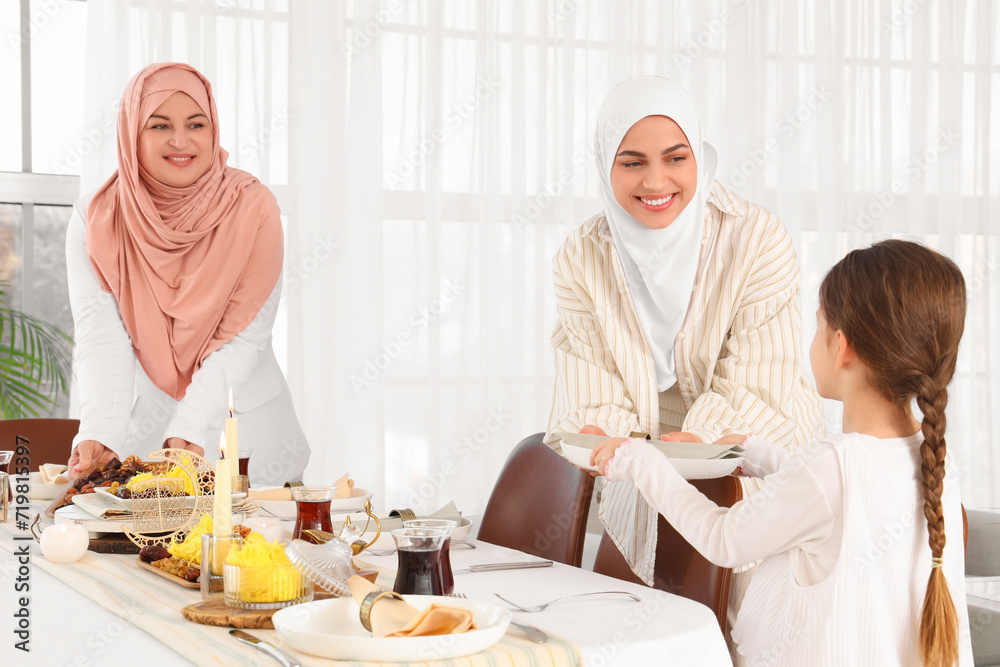 Young Muslim woman with her mother and little daughter setting table at home. Ramadan celebration Young Muslim woman with her mother and little daughter setting table at home. Ramadan celebration