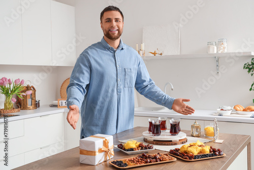 Young Muslim man celebrating Ramadan at table in kitchen