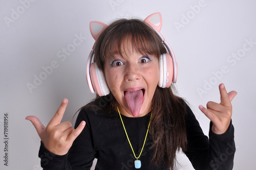 pré adolescente mostrando a lingua engraçada  e feliz com fones de ouvido escutando musicas