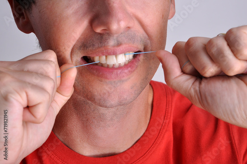 homem passando fio dental nos dentes , limpeza dental  photo