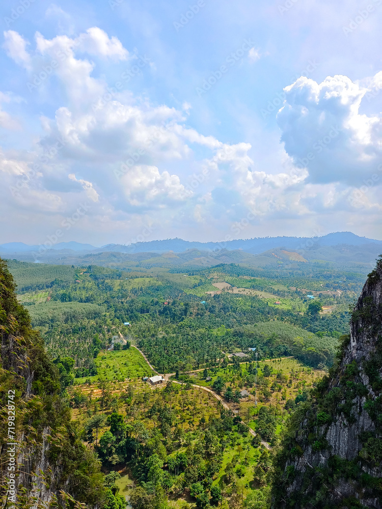 Fototapeta premium Mountain view on a high cliff with nature and green trees surrounding . Aerial view of Beautiful natural scenery mountain. Wallpaper background nature cloud sky. Happy relax holiday 