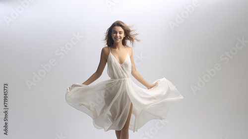 full-body fashion portrait of a beautiful woman in a long, flowing white gala dress, the light fabric gracefully draping her figure against a chic white and gray background. Generative AI. © Surachetsh